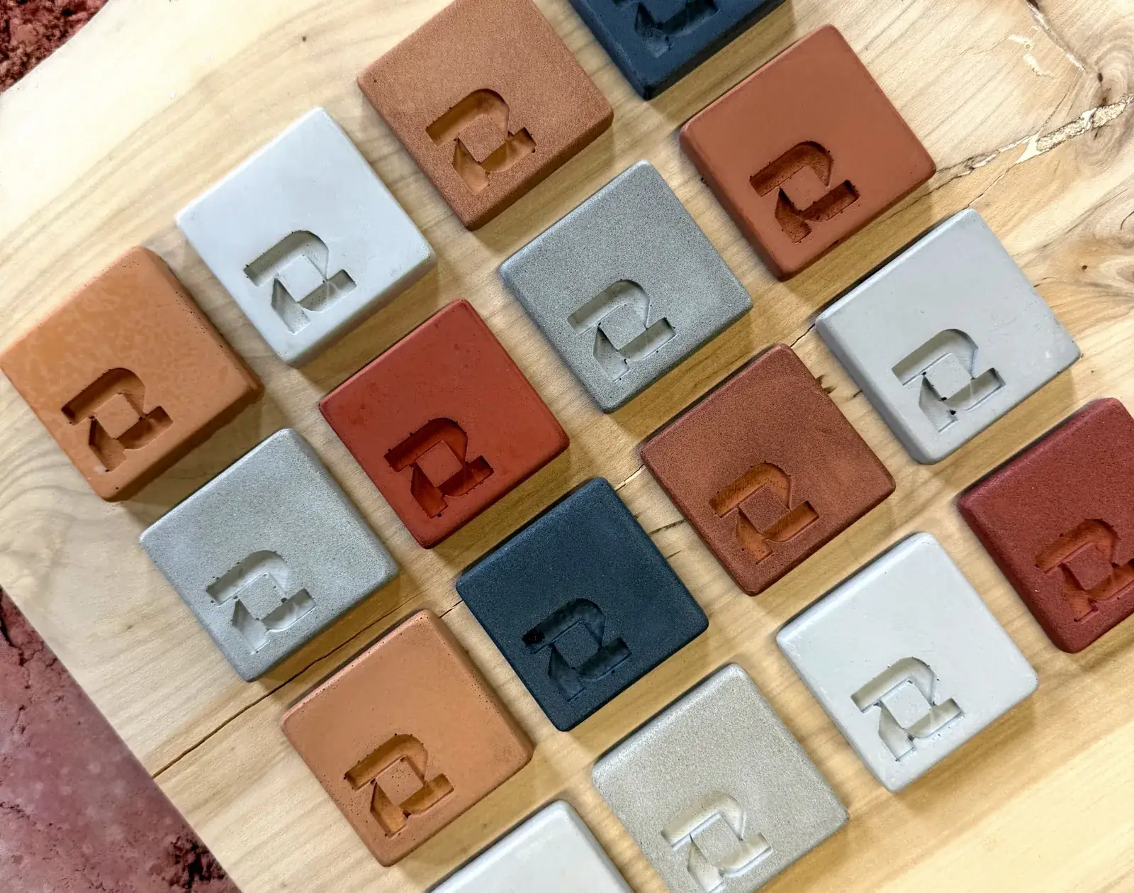 ROKA concrete samples in a spread of colours, from pale grey to terracotta, laid on an oak slab